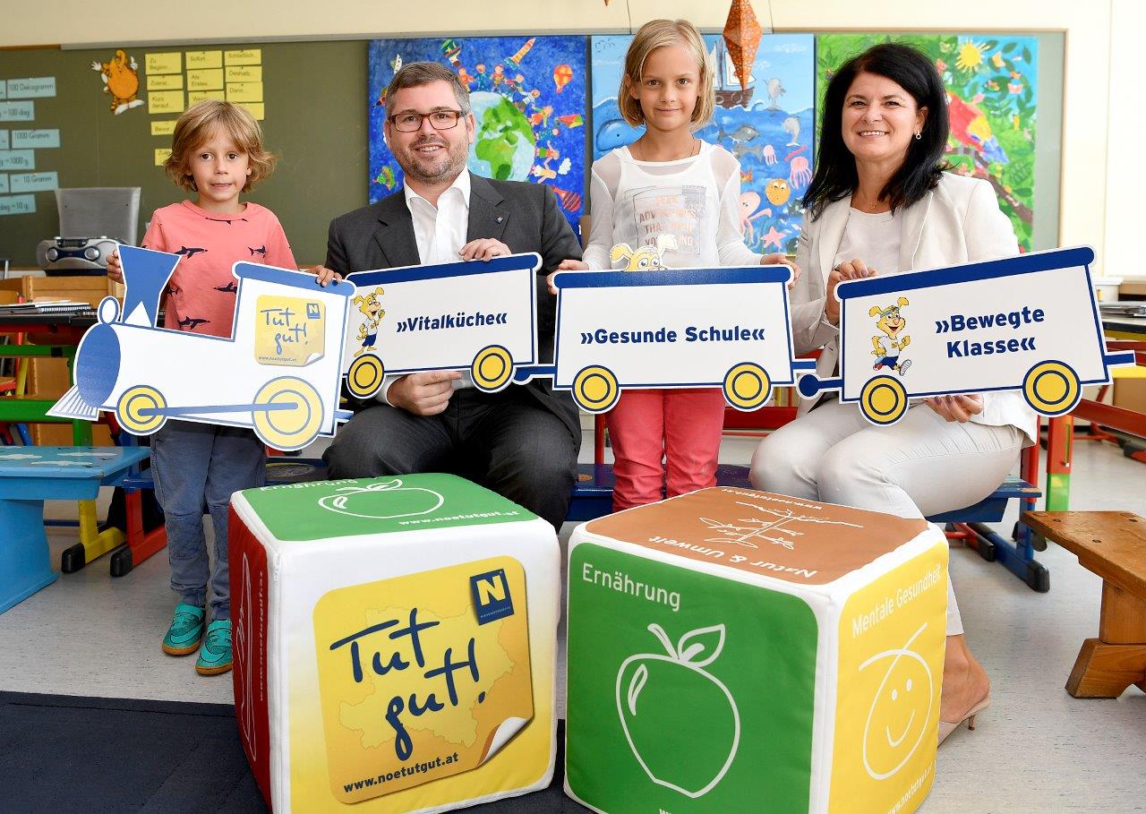 Landesrat Ludwig Schleritzko, Sigrid Bannert (Direktorin Praxisvolksschule Krems) und die Kinder der Praxisvolksschule Krems freuen sich über die brandneuen „Tut gut!“-Jausenboxen. (Bildquelle: NLK / Filzwieser)