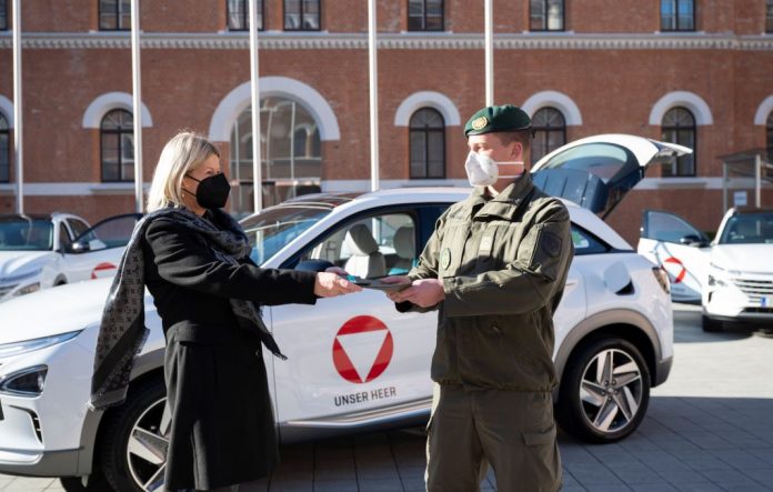 Verteidigungsministerin Klaudia Tanner übergibt die Fahrzeugpapiere eines neuen Wasserstoffautos an einen Kraftfahrer (Bildquelle: HBF/Carina Karlovits)
